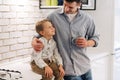 Father and son smiling while spending time together at home in the kitchen