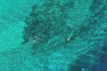 Father and son snorkels through tropical, turquoise waters, aerial view