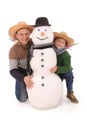 Father and son with snowman with scarf and hat