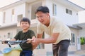 Father and son spend time together having fun learning to ride a bicycle in front of their new home Royalty Free Stock Photo