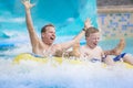 Father and son splashing down a water slide at an aquapark