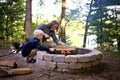 Father and Son Starting Campfire in Fire Ring at Campground Overlooking a Lake in the Woods