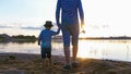 Father and son in striped shirts with fishing rods staying on the riverside at sunset Royalty Free Stock Photo