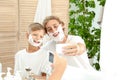 Father and son taking selfie with shaving foam on faces