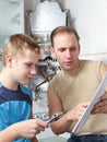 The father and the son-teenager together look the instruction on repair a gas water heater.Portrait