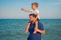 Father son together outside showing finger sea horizon back Man child spending time vacation enjoying summer