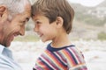 Father and son (5-6) touching foreheads on beach close-up