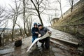 Father and son tourist look at map, stand on wet path to an ancient medieval castle fortress in rain