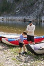 Father and son tourists outdoors spending time together. Schoolboy pumps catamaran with foot-powered pump, dad looks at him Royalty Free Stock Photo