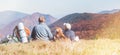 Father and son travelers with their beagle dog sit together in mountain valley with beautiful hills view. Trekking with kids and