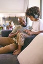 Father And Son Using Digital Tablet With Headphones At Home With Multi-Generation Family Behind Royalty Free Stock Photo