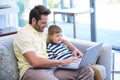 Father and son using laptop on the couch Royalty Free Stock Photo