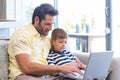 Father and son using laptop on the couch Royalty Free Stock Photo