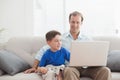 Father and son using laptop on the couch Royalty Free Stock Photo