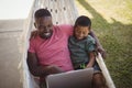 Father and son using laptop while relaxing on hammock Royalty Free Stock Photo