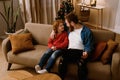 Father and son using laptop while sitting on sofa with Christmas tree on background Royalty Free Stock Photo