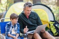 Father and son using laptop by tent in forest Royalty Free Stock Photo