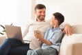 Father And Son Using Phone And Laptop Sitting At Home Royalty Free Stock Photo