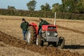 Father and son with vintage red tractor ploughing