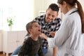 Father and son visiting pediatrician. Doctor examining patient`s throat in hospital Royalty Free Stock Photo