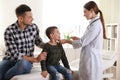 Father and son visiting pediatrician. Doctor examining little patient`s throat Royalty Free Stock Photo