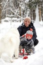 Father and son walking in snowy forest with his beagle dog in pine forest. Family walking with pets and winter outfit Royalty Free Stock Photo