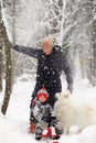 Father and son walking in snowy forest with his beagle dog in pine forest. Family walking with pets and winter outfit Royalty Free Stock Photo