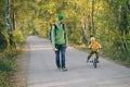 Father and son walking together on empty road in autumn park, child boy learning to ride by bicycle. Beautiful nature in fall Royalty Free Stock Photo