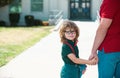 Father and son walking trough school park. Portrait of happy nerd pupil holding teachers hand. Royalty Free Stock Photo