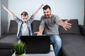 Father and son watching football in a laptop at home. Emotional man and boy, cheering favorite team. The concept of family Royalty Free Stock Photo