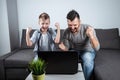 Father and son watching football in a laptop at home. Emotional man and boy, cheering favorite team. The concept of family Royalty Free Stock Photo