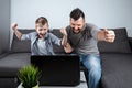 Father and son watching football in a laptop at home. Emotional man and boy, cheering favorite team. The concept of family Royalty Free Stock Photo