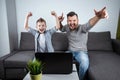 Father and son watching football in a laptop at home. Emotional man and boy, cheering favorite team. The concept of family Royalty Free Stock Photo