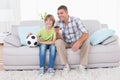 Father and son watching soccer match on sofa Royalty Free Stock Photo