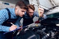 Father and son work at the auto service. Two mechanics work with the details of the car. Royalty Free Stock Photo