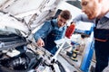 Father and son work at the auto service. Two mechanics work with the details of the car. Royalty Free Stock Photo