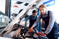 Father and son work at the auto service. Two mechanics work with the details of the car. Royalty Free Stock Photo