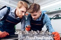 Father and son work at the auto service. Two mechanics work with the details of the car. Royalty Free Stock Photo