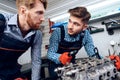 Father and son work at the auto service. Two mechanics work with the details of the car. Royalty Free Stock Photo