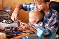 Father and son in workshop repairing some stuff. Cute boy exploring tools. Fatherhood and transfer of experience concept