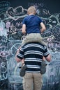 Father and son writing on big blackboard