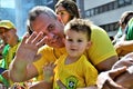 A father and son in yellow wave at the demonstration on paulista avenue