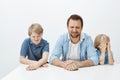 Father and sons feeling upset while mom at work. Portrait of hungry displeased european family of male boys and dad Royalty Free Stock Photo