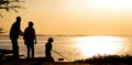 father and sons fishing in the river sunset background. Silhouette of man and two boys fishing at lake Royalty Free Stock Photo