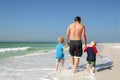 Father and Sons Holding Hands Walking Through Ocean