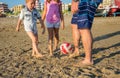 Father and sons playing soccer on the beach