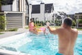 Father splashing water on his daughter and wife in the swimming pool Royalty Free Stock Photo