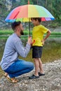 Fathers day outdoor. Father and son under a rainbow color umbrella