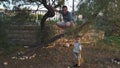 Father squats on the tree to teach kids to play outdoors.