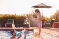 Father Squirting Son With Water Pistol Playing In Swimming Pool On Summer Vacation